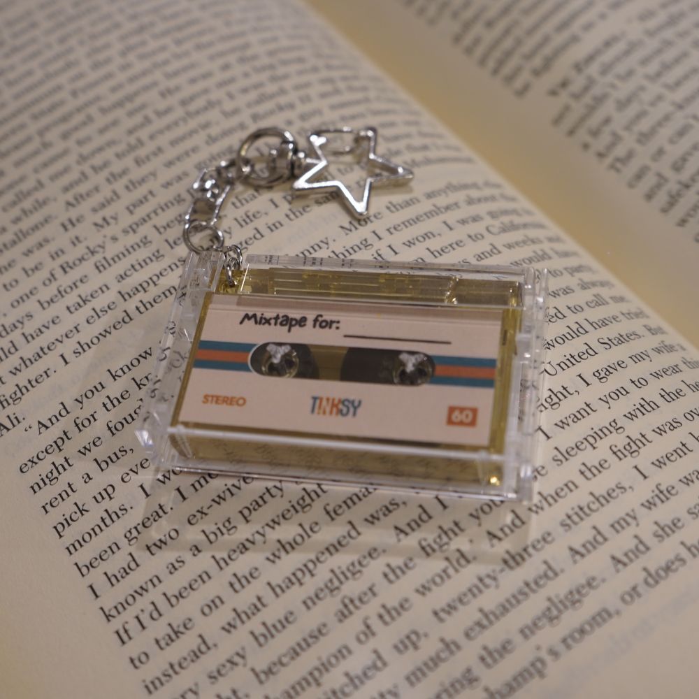 Mini Cassette NFC keychain with a star charm on a book page